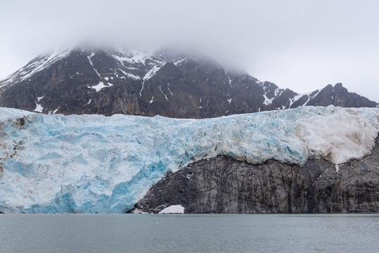 Melting glacier on Spitsbergen with a rock getting free and visible.