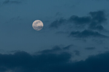 Naklejka na ściany i meble A full moon in a cloudy blue sky background