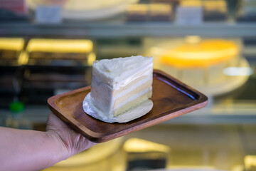 Piece of Coconut Cake on wooden plate in shop