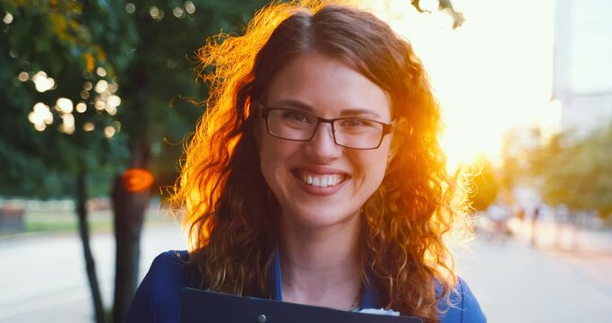Girl with documents folder has fun closing her face, laughing and smiling.