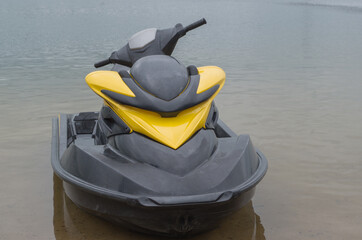 Water scooter boat with black deck and steering part and yellow streamlined vertical part standing...