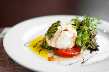 Italian burrata cheese with tomatoes, herbs, pesto and olive oil.