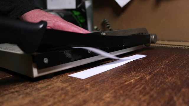 Cutting paper with a hand guillotine.