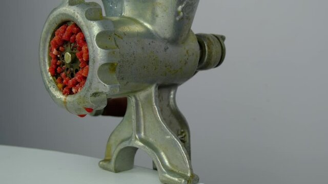 Cooking minced meat with a manual meat grinder. Close-up of front part of mincing-machine with mincemeat in. Showing the forcemeat process.