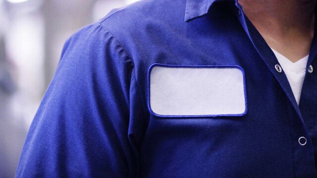 Blue uniform shirt with empty name white patch, unrecognizable worker or employee Identification.