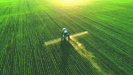 Tractor spray fertilizer on green field drone high angle view, agriculture background concept. - obrazy, fototapety, plakaty