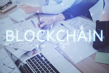 Cryptocurrency hologram over woman's hands writing background. Concept of blockchain. Multi exposure