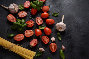 Pieces of cut fresh tomatoes over dark background. 
Tomato with droplets of water with basil leaves. Close up