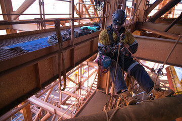 Industrial rope access rigger miner worker wearing safety harness, helmet working at height...