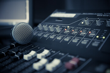 Close-up microphone on sound mixer equipment for recording, editing, and sound system control concept.