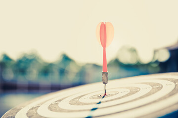 Bullseye or dart board has dart arrow throw hitting the center of a shooting target for business...