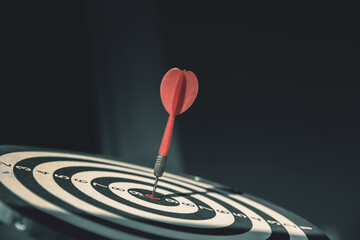 Bullseye or dart board has dart arrow throw hitting the center of a shooting target for business...