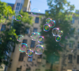 Multi-colored soap bubbles fly in the air against a blurred city