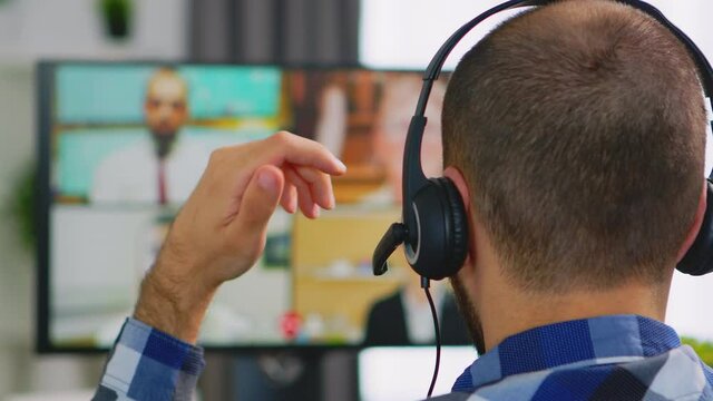 Young entrepreneur in wheelchair turning on headphone during a business video call. Handicapped invalid paralysed freelancer, immobilized entrepreneur working from home, ilness and disability