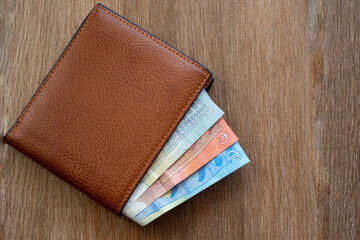 New leather wallet with euro money on a wooden background