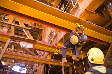 Rope access maintenance worker wearing safety harness hard hat working at height descending on rope...