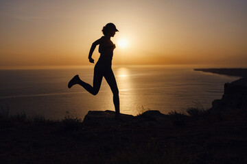 Side view of fitness woman running on a road by the sea.