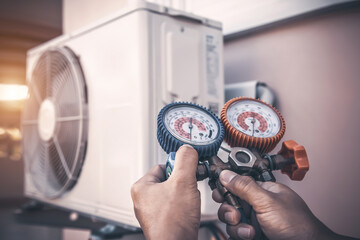 Air repair mechanic using measuring pressure gauge equipment for filling home air conditioner after...