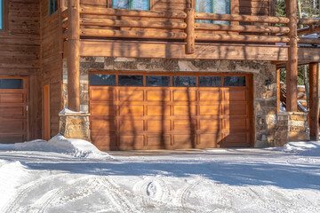 Facade of a luxury wooden home in Park City Utah with snowy driveway in winter