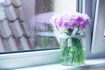 A bouquet of beautiful pink flowers in a vase. On the windowsill. Summer