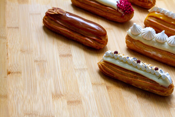 assorted eclairs with different decor on a wooden table. Copy space. Menu, recipe, ad concept.