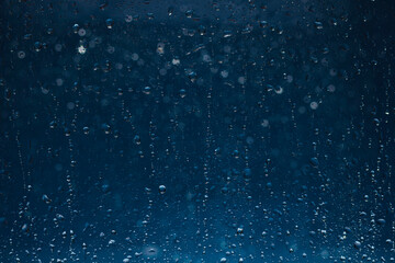 Naklejka na ściany i meble Blue water drops background. Blue water drops on a boat glass background. Water drops on boat glass blue bokeh background.