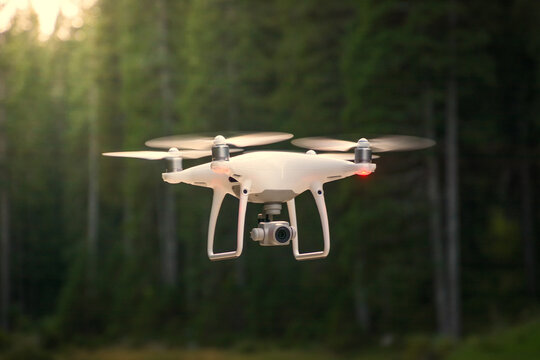 Drone flying in nature. Green trees in background. Low angle, shallow depth of field