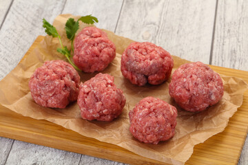 Raw meatball over wooden background