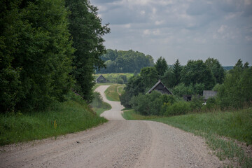 Fototapeta na wymiar A winding gravel road between forest trees in the countryside in summer
