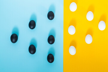 Six black eggs and six white eggs on a blue background with yellow, pop art, abstract.