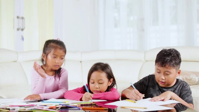 Group of adorable kids coloring a paper on the table