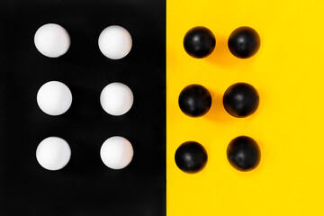 Black eggs with six white eggs, on a black background with yellow, contrast, abstract.