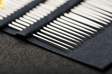 Sewing needles on a black background in a row.