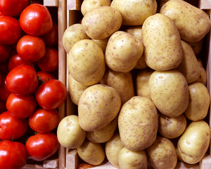 Potatoes and tomatoes in a wooden box.