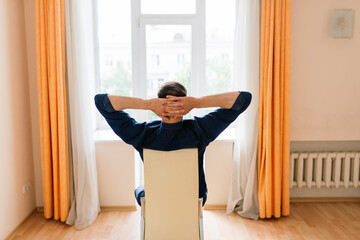 Fototapeta na wymiar Relaxed young man resting from work. Man enjoy break stretching in home office workplace, isolation
