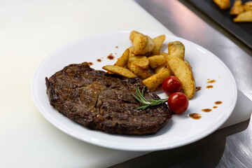 Grilled steak with baked potatoes and cherry tomatoes.