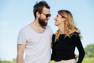 Man and woman in love looking at each other and smiling. Over blue sky