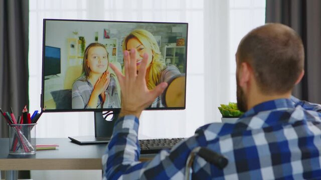 Man with walking disability in wheelchair having a conversation with his family on video call. Handicapped invalid paralysed freelancer, immobilized entrepreneur working from home