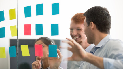 Smiling diverse employees with executive working on project together in office, looking on colorful...
