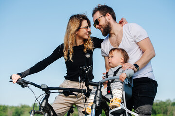 Man and woman looking at each other, sharing bike ride with their baby
