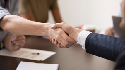 Obraz na płótnie Canvas Close up business partners handshaking after successful negotiations wide horizontal image, making agreement, greeting, employees shaking hands at briefing, congratulating with promotion