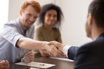 Happy employees shaking hands at briefing, sharing teamwork success, leader congratulating with promotion, business partners handshaking close up after successful negotiations, making agreement
