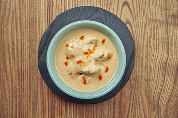 Traditional, georgian Satsivi or chicken in walnut sauce in blue bowl on wooden background.