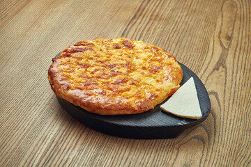 Delicious Georgian khachapuri - closed baked pie with homemade cheese on a wooden background