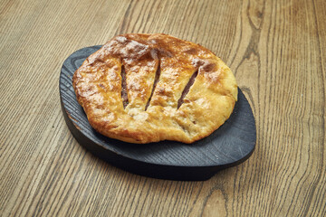Delicious Georgian khachapuri - closed baked pie with minced meat on a wooden background