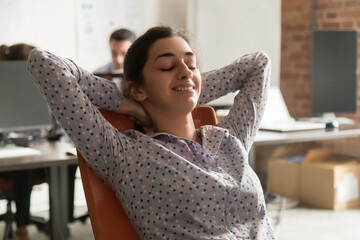 Calm satisfied Indian businesswoman employee sitting in comfortable office chair, smiling intern...