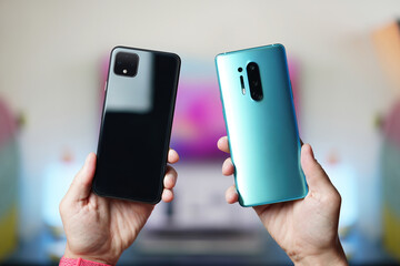 Man hands holding side by side two smartphones. Comparing, analyzing or matching two new...