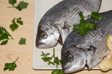 fresh bream or sea bream on the plate with parsley and lemon