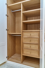 White wardrobe with wooden drawers and shelves. Wooden filling of wardrobe