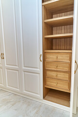 White wardrobe with wooden drawers and shelves. Wooden filling of wardrobe
